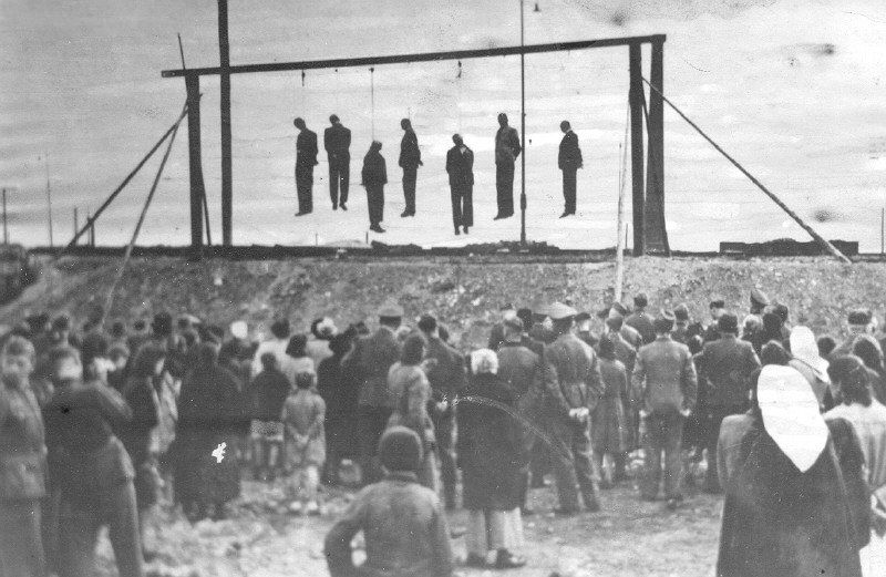 Inhabitants of the Lvov ghetto viewing the bodies of seven members of the Judenrat who were hanged.